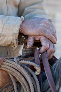 Picture of old cowboy holding onto a saddle